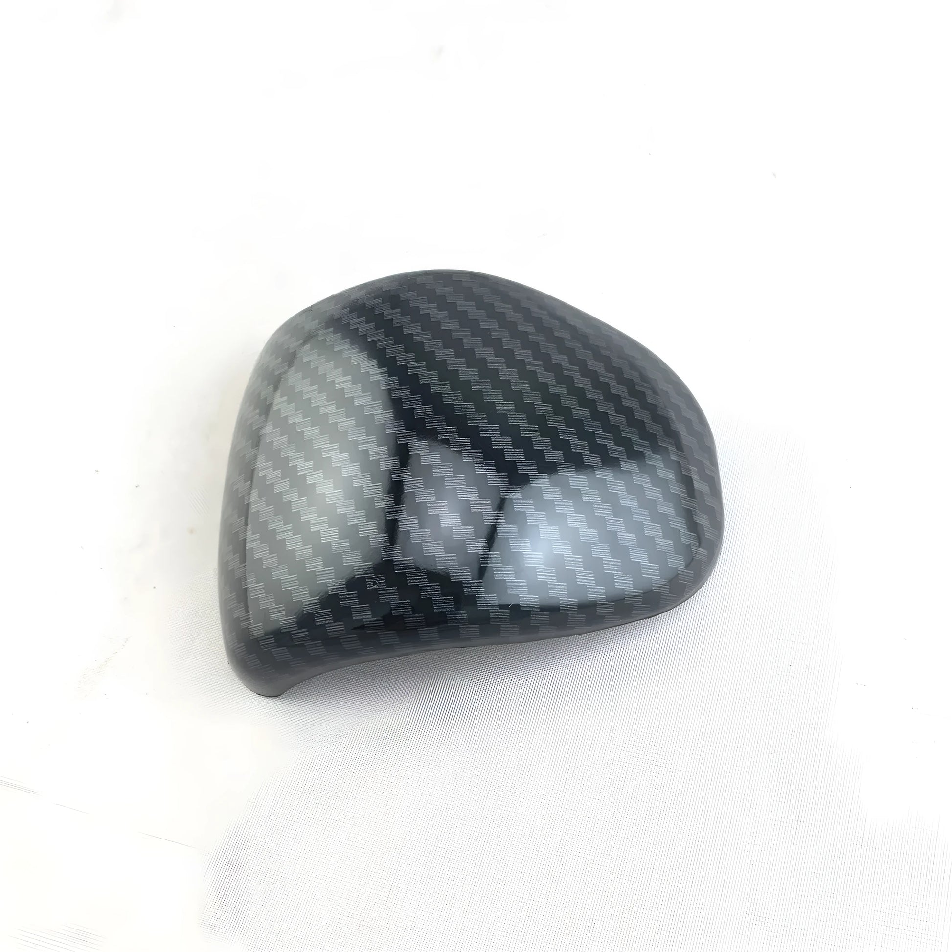 Black carbon fibre effect plastic cover for a car gear shift knob.
