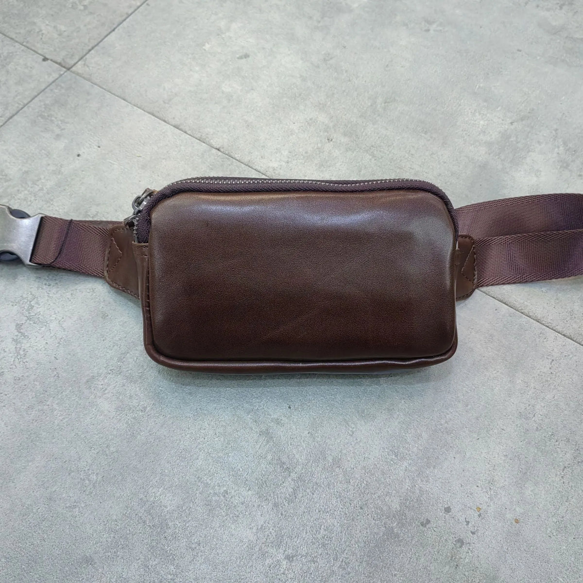 Men's small leather crossbody bag in black showing compact dimensions and crossbody strap