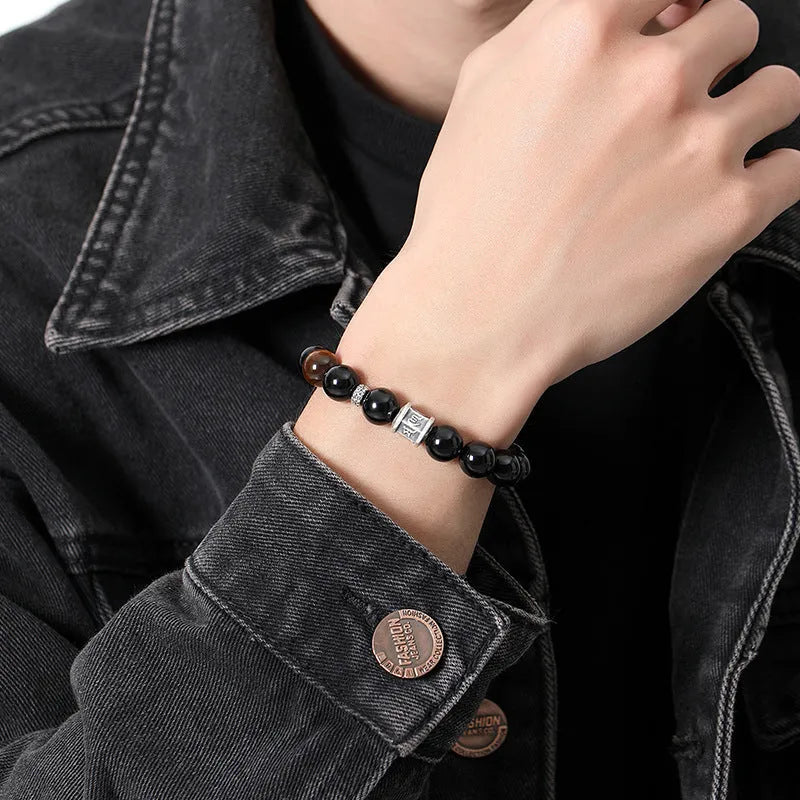 Men's black obsidian bracelet with 10mm prayer wheel beads and silver accents showing hand-woven construction