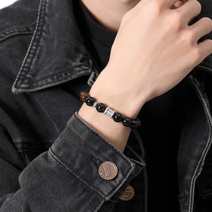 Men's black obsidian bracelet with 10mm prayer wheel beads and silver accents showing hand-woven construction