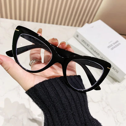 Women's black floral cat's eye reading glasses with large frames on a wooden table.