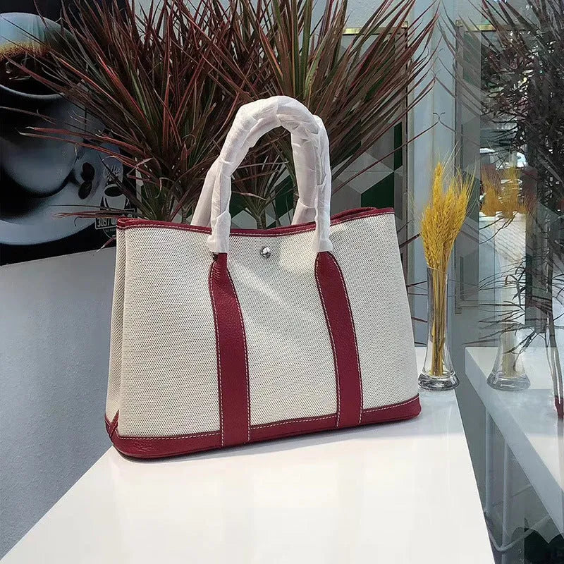 Canvas and leather tote bag in bucket shape with crossbody strap, shown in black, brown, gray or red colour options