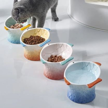 Set of four blue fish-shaped ceramic cat bowls with a tilted design on a wooden floor.