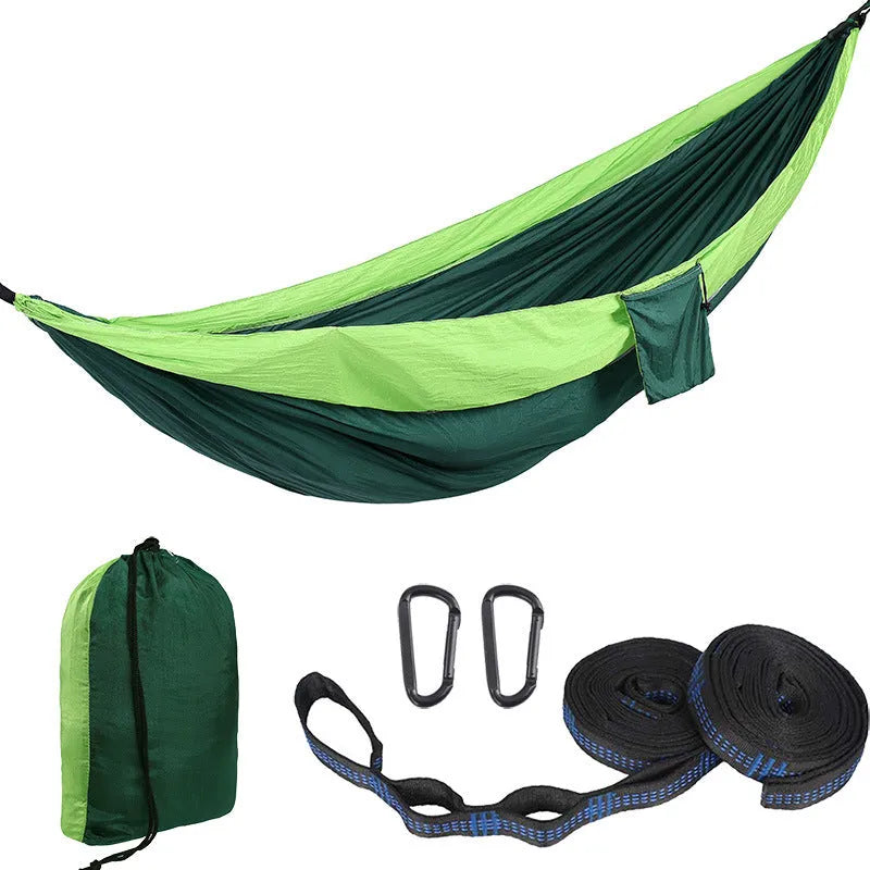 Parachute cloth double camping hammock in chosen colour, with black buckles and round ropes on a tree.