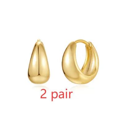 Pair of golden geometric clip-on earrings with a round design and screw-back mechanism on a white background.