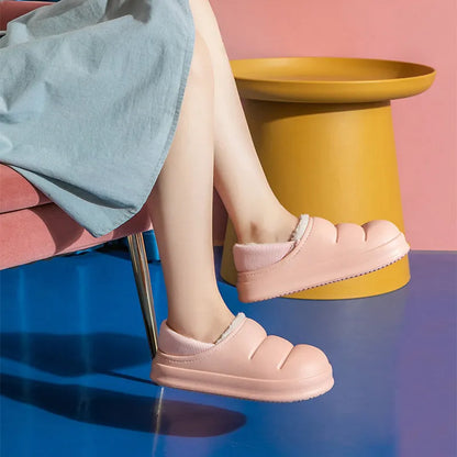 Pair of yellow waterproof EVA slippers with plush lining and a textured non-slip sole on a wooden floor.