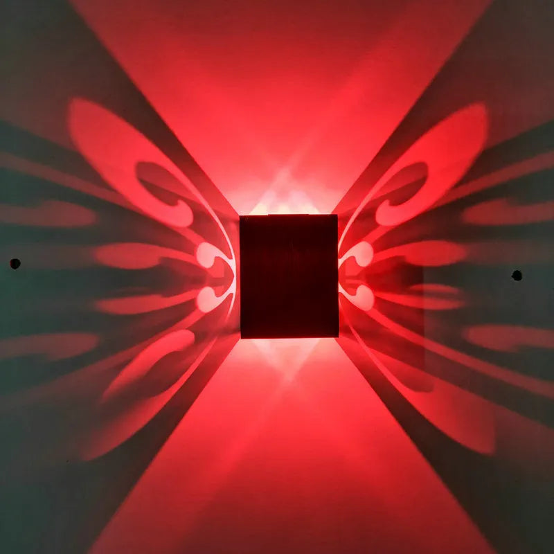 Modern aluminium butterfly-shaped LED wall lamp with colour-changing lights on a plain wall