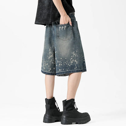 Men's retro blue denim shorts with ripped knees and splash ink detailing, straight leg mid-thigh cut.