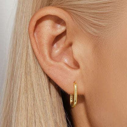 Geometric gold-tone stud earrings with a round centre on an earclip back, shown from the front.