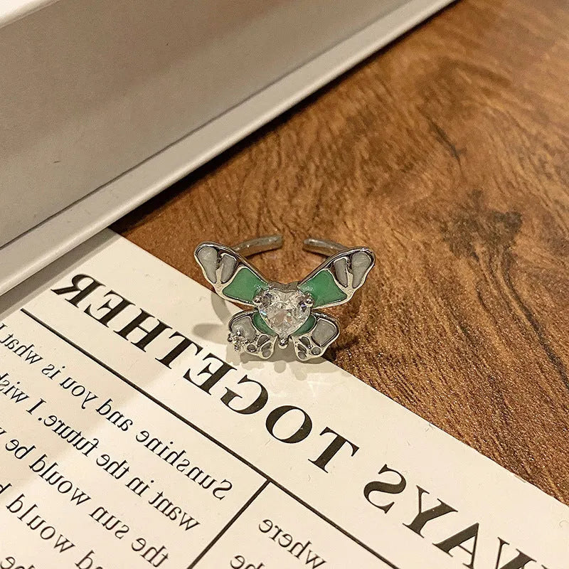 Copper butterfly women's ring with an open loop design on a plain background.