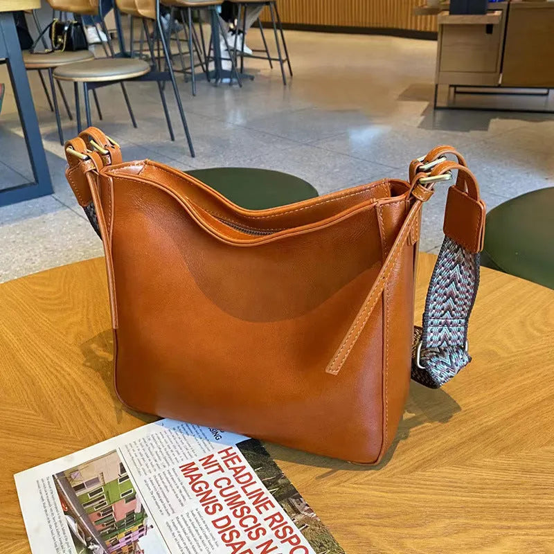 Women's black genuine leather shoulder messenger bag showing structured square shape and single strap.