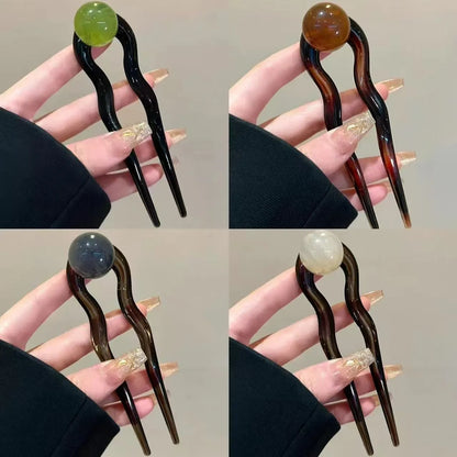 A set of U-shaped acrylic hair barrettes with a simple ball decoration in beige, caramel, and dark grey colours.