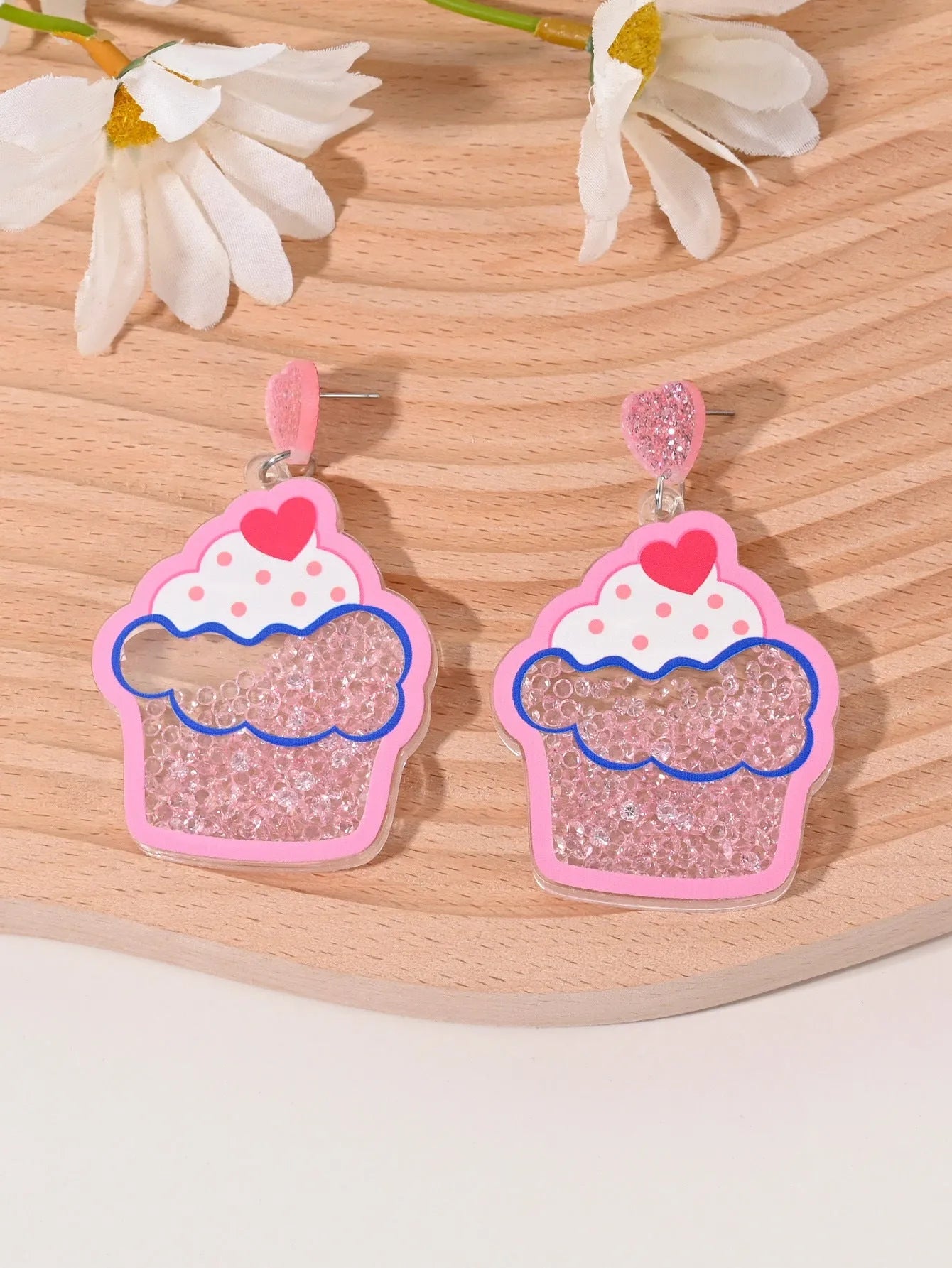 A pair of colourful acrylic earrings shaped like a strawberry and a cherry on a woman's ear.
