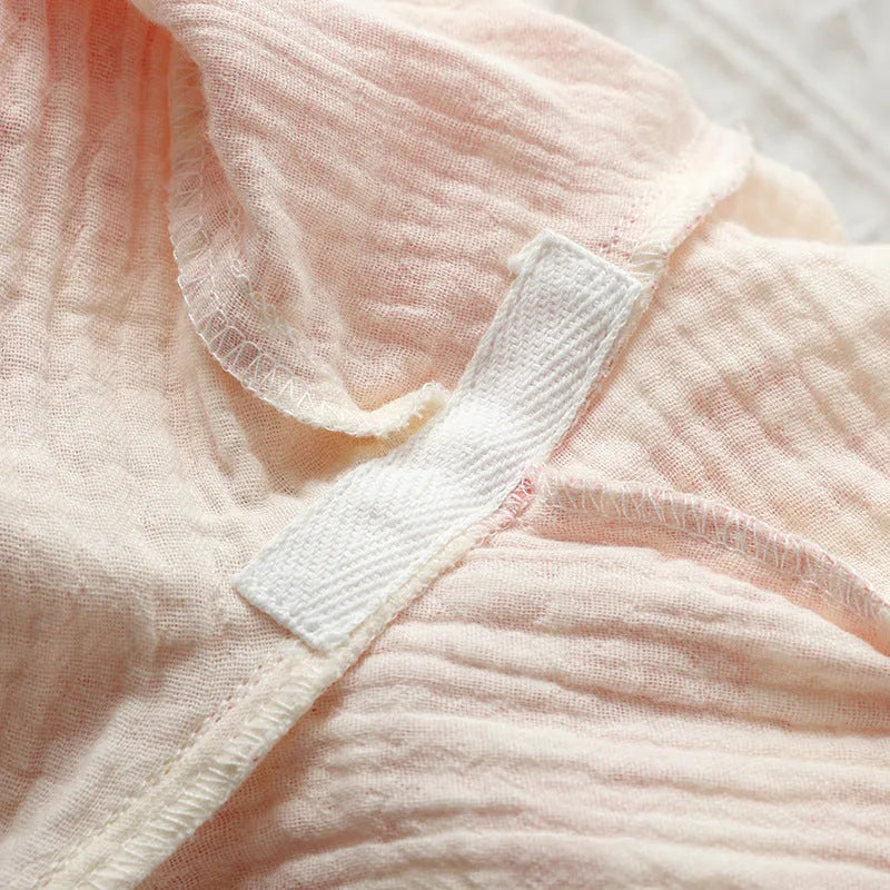 Women's pink pure cotton gauze lace-up top and trousers homewear set laid flat.