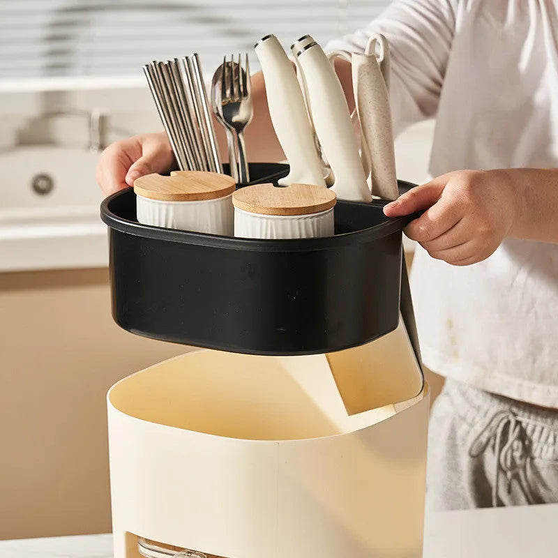 White rotating plastic kitchen storage bucket and a separate white spice box with four compartments on a countertop.