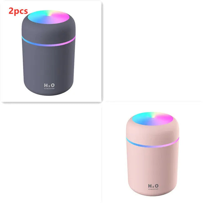Pink USB desktop humidifier with LED lights and water tank on wooden desk