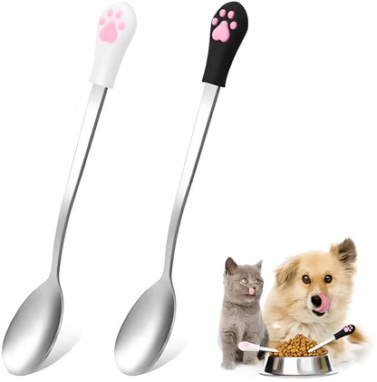 Two pet food spoons with cat paw designs - one white and one black with stainless steel and silicone construction
