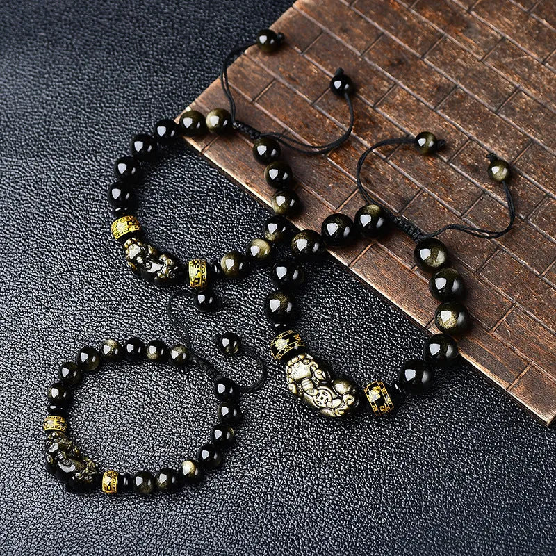 Handmade golden obsidian Pi Xiu bracelet with Chinese zodiac design on wrist.