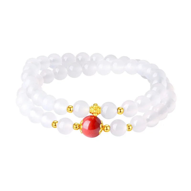 Close-up of a women's double layer bracelet with polished white agate and jequirity bean beads.