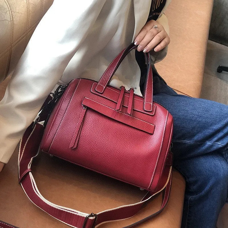 Genuine leather horizontal messenger bag in wine red with shoulder strap and internal zippered compartments.