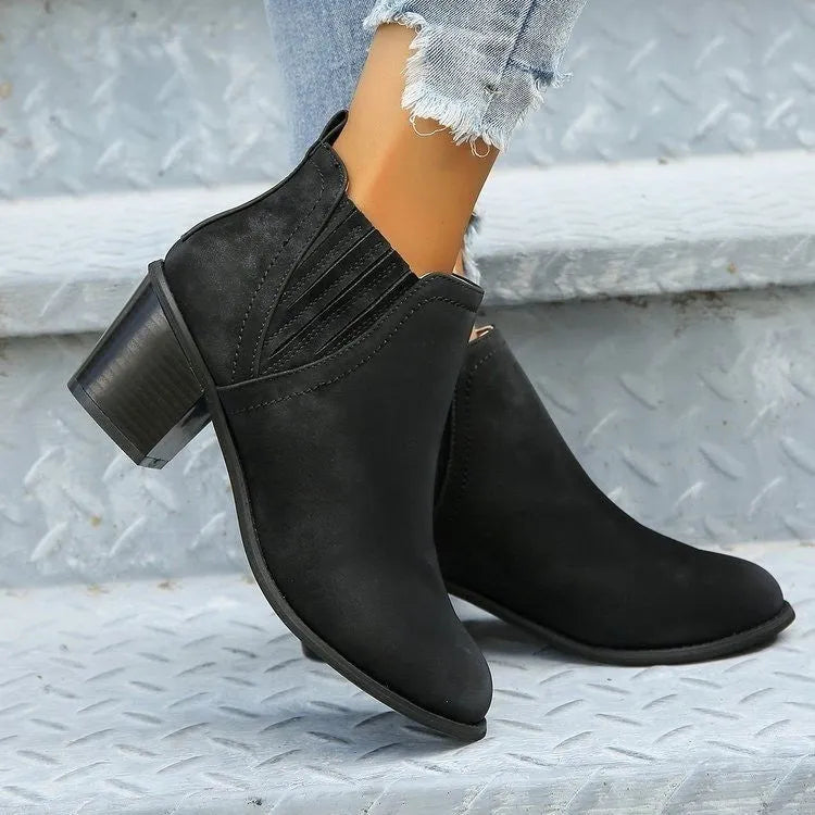 Black women's pointed toe ankle boots with a thick low square heel and slip-on design.