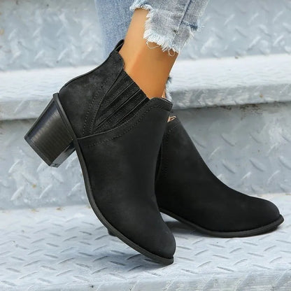 Black women's pointed toe ankle boots with a thick low square heel and slip-on design.
