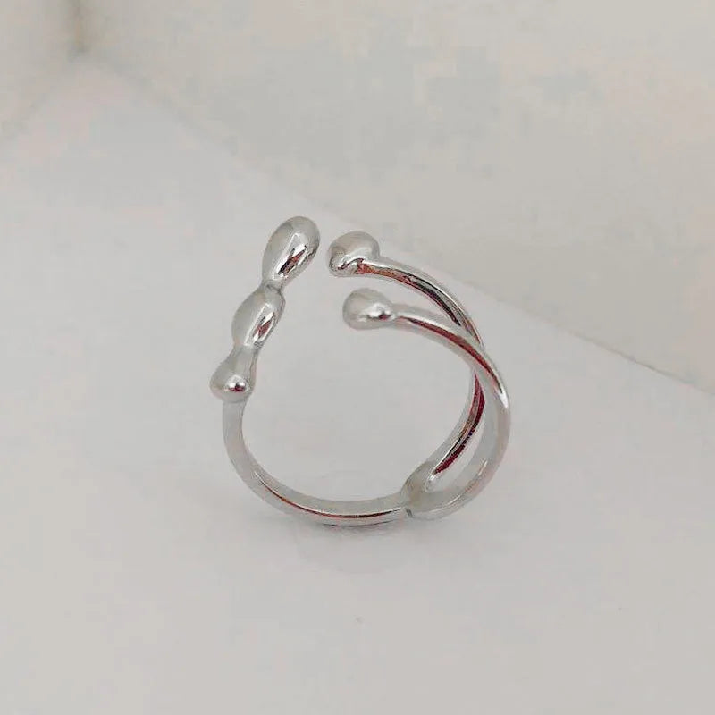 A minimalist brass ring with a small spherical detail on a plain band, shown in gold tone.
