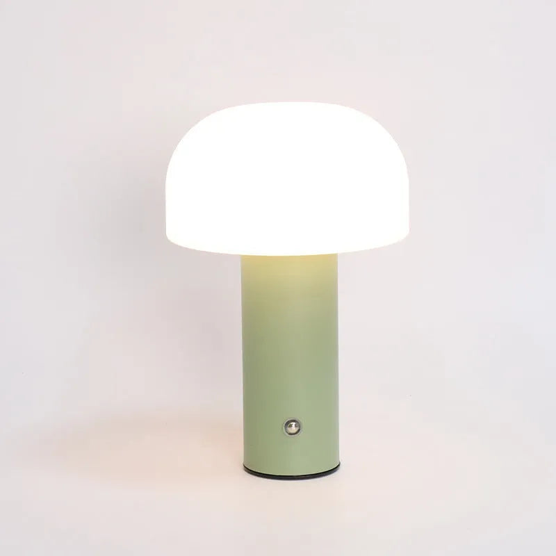 A small white USB and plug-in table lamp with a cylindrical shade, sitting on a wooden desk next to a laptop.