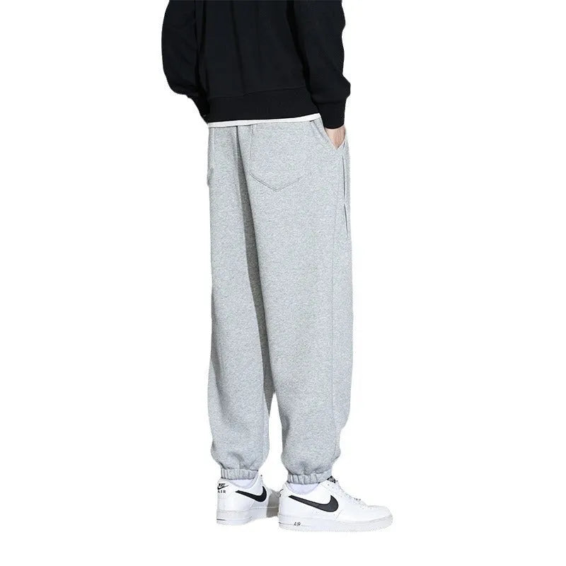 Man wearing loose grey sports trousers with an elasticated drawstring waistband.