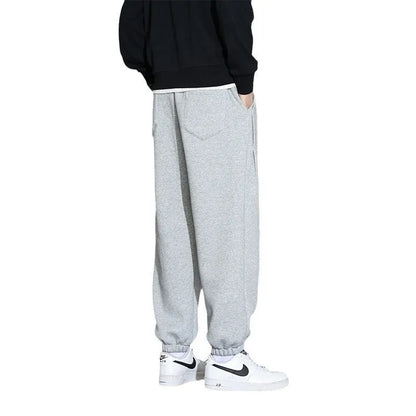 Man wearing loose grey sports trousers with an elasticated drawstring waistband.