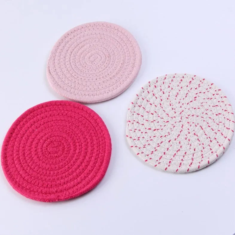 Three round grey cotton cord coaster placemats on a wooden table, each 18cm in diameter.