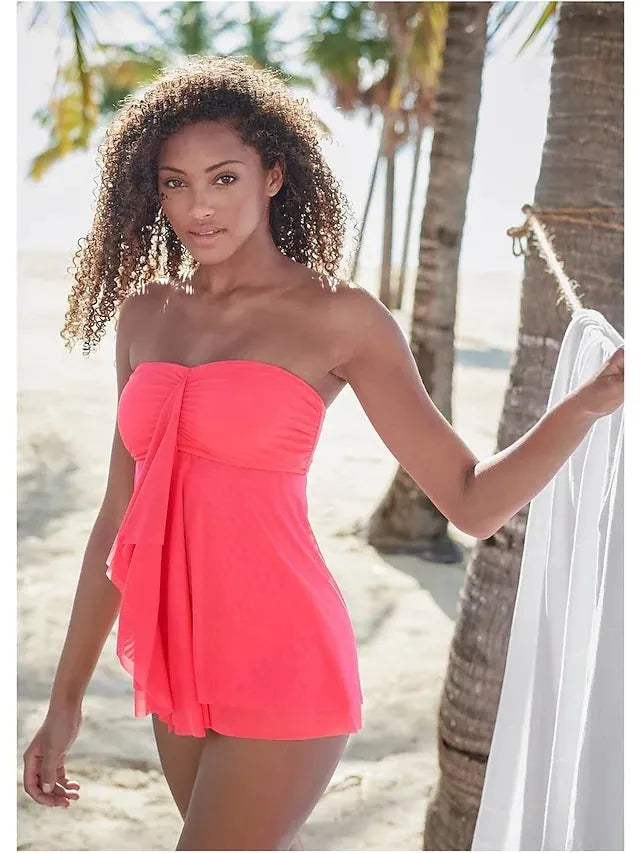 Woman wearing a strapless solid colour one-piece swimsuit or swim dress on the beach.