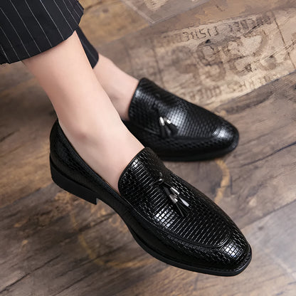 Men's black pointed toe slip on shoes with a tassel detail on the upper.