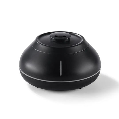 White round ultrasonic aroma diffuser humidifier with colourful simulated flame light effect on a wooden desk.