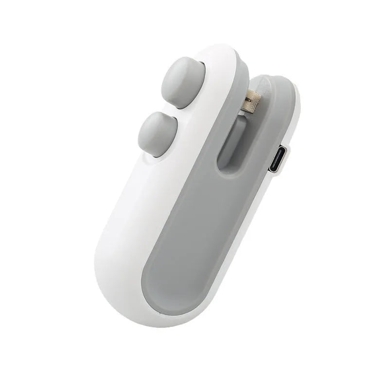 Handheld white portable heat sealer with USB Type-C port and magnetic back on a metal surface.