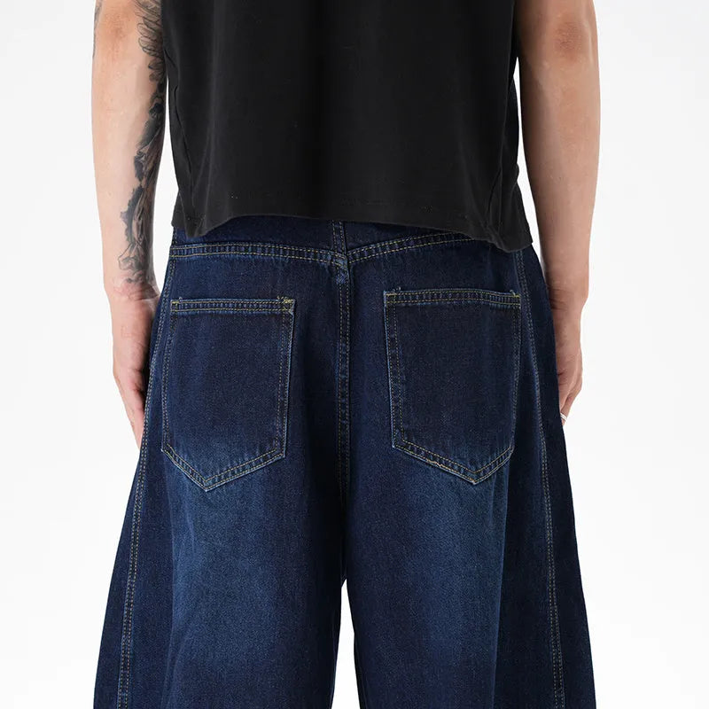 Dark blue distressed wide leg Machete jeans laid flat, showing washed denim texture.