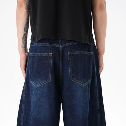 Dark blue distressed wide leg Machete jeans laid flat, showing washed denim texture.
