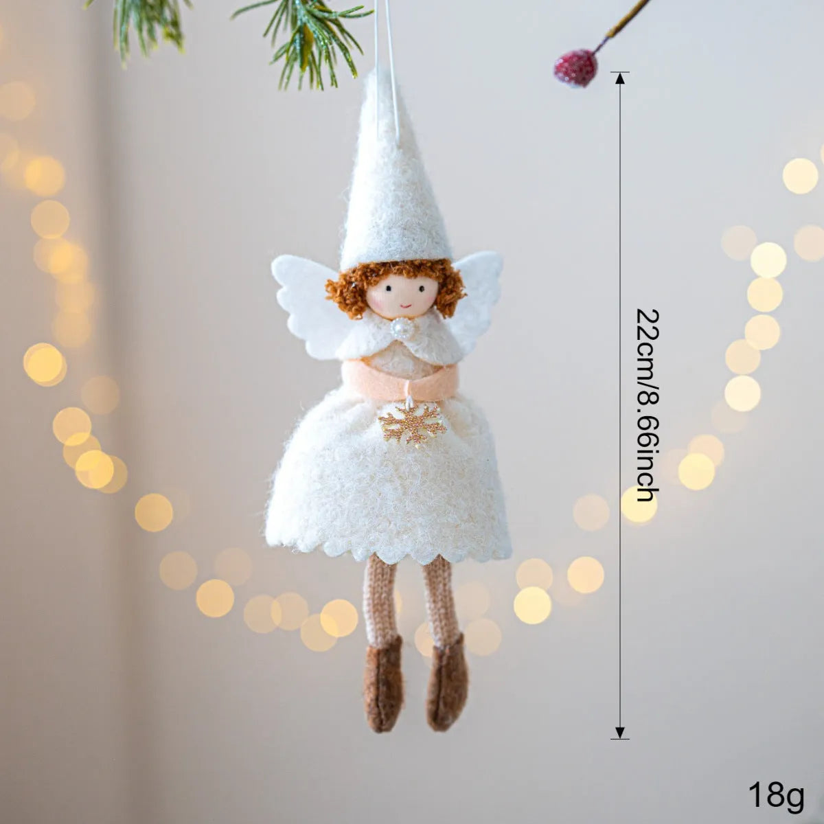 White and pink cloth felt Christmas angel skirt pendant ornament on a tree branch.