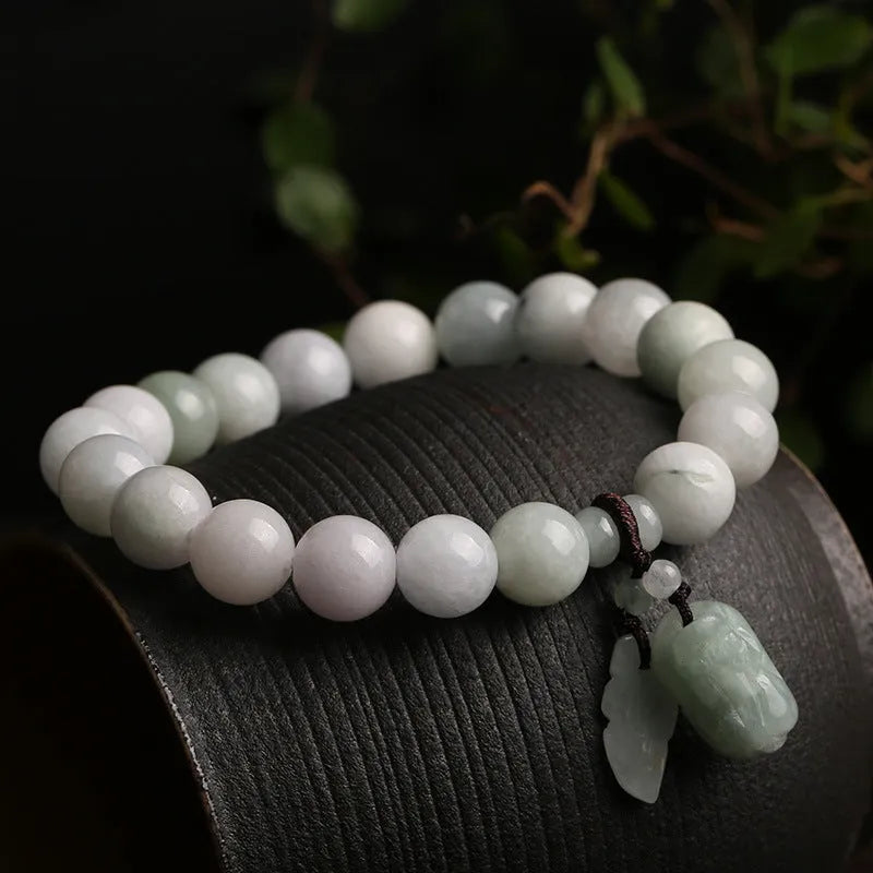 Natural green jade charm bracelet with carved apple and geometric stone pendants.