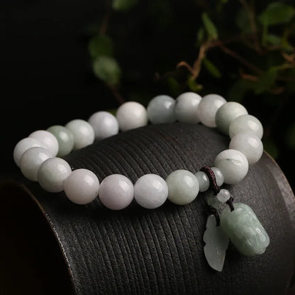 Natural green jade charm bracelet with carved apple and geometric stone pendants.