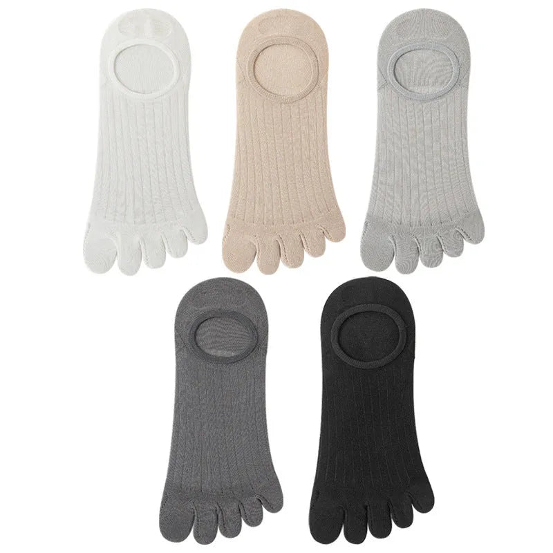 Pair of solid colour modal five-finger invisible socks on a wooden surface, showing toe separation and low-cut design.