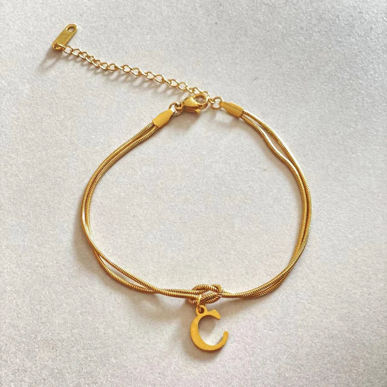 Elegant letter charm bracelets for women in gold and silver tones, featuring a delicate snake chain design and personalised letter charms.