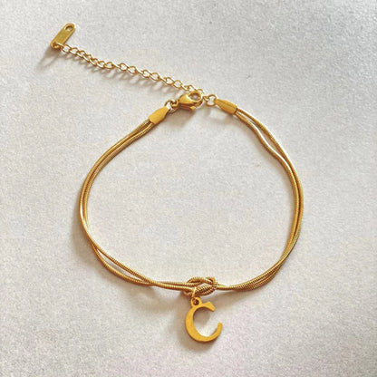 Elegant letter charm bracelets for women in gold and silver tones, featuring a delicate snake chain design and personalised letter charms.