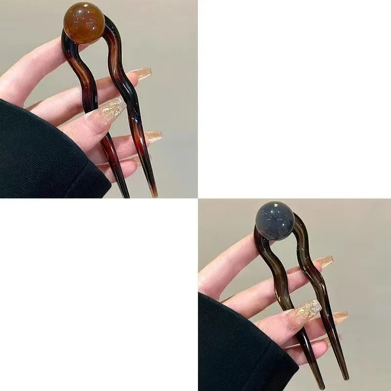 A set of U-shaped acrylic hair barrettes with a simple ball decoration in beige, caramel, and dark grey colours.