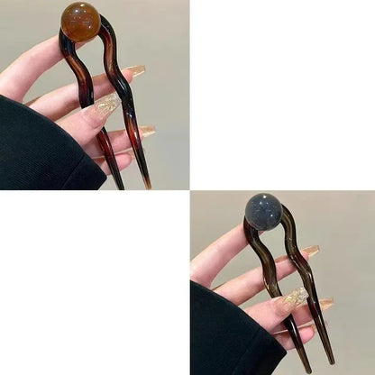 A set of U-shaped acrylic hair barrettes with a simple ball decoration in beige, caramel, and dark grey colours.