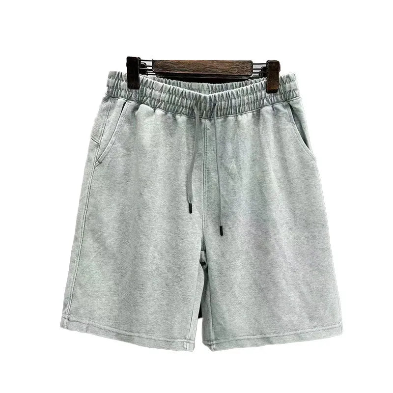 Man wearing loose-fit, straight-leg distressed cotton shorts in a solid colour