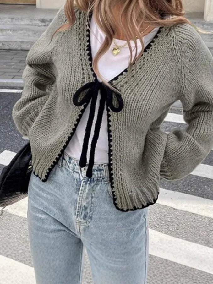 Grey lace-up front cardigan sweater with long sleeves and a crocheted flower detail.