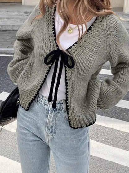 Grey lace-up front cardigan sweater with long sleeves and a crocheted flower detail.