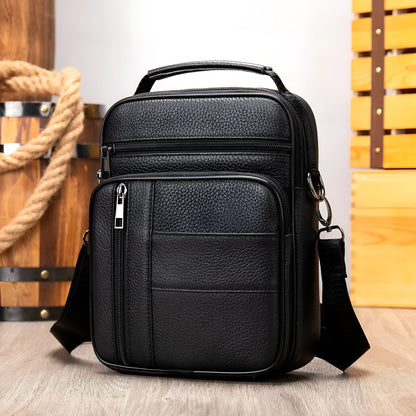 Vertical black genuine cowhide leather shoulder bag with a zip opening and soft handle, shown with internal organiser pockets.