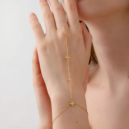 Gold stainless steel women's bracelet with geometric design of eight pointed stars and flowers.